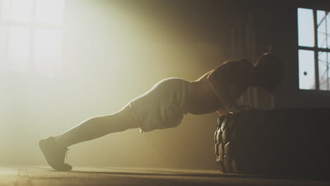 man performing push-ups on a tire in a gym