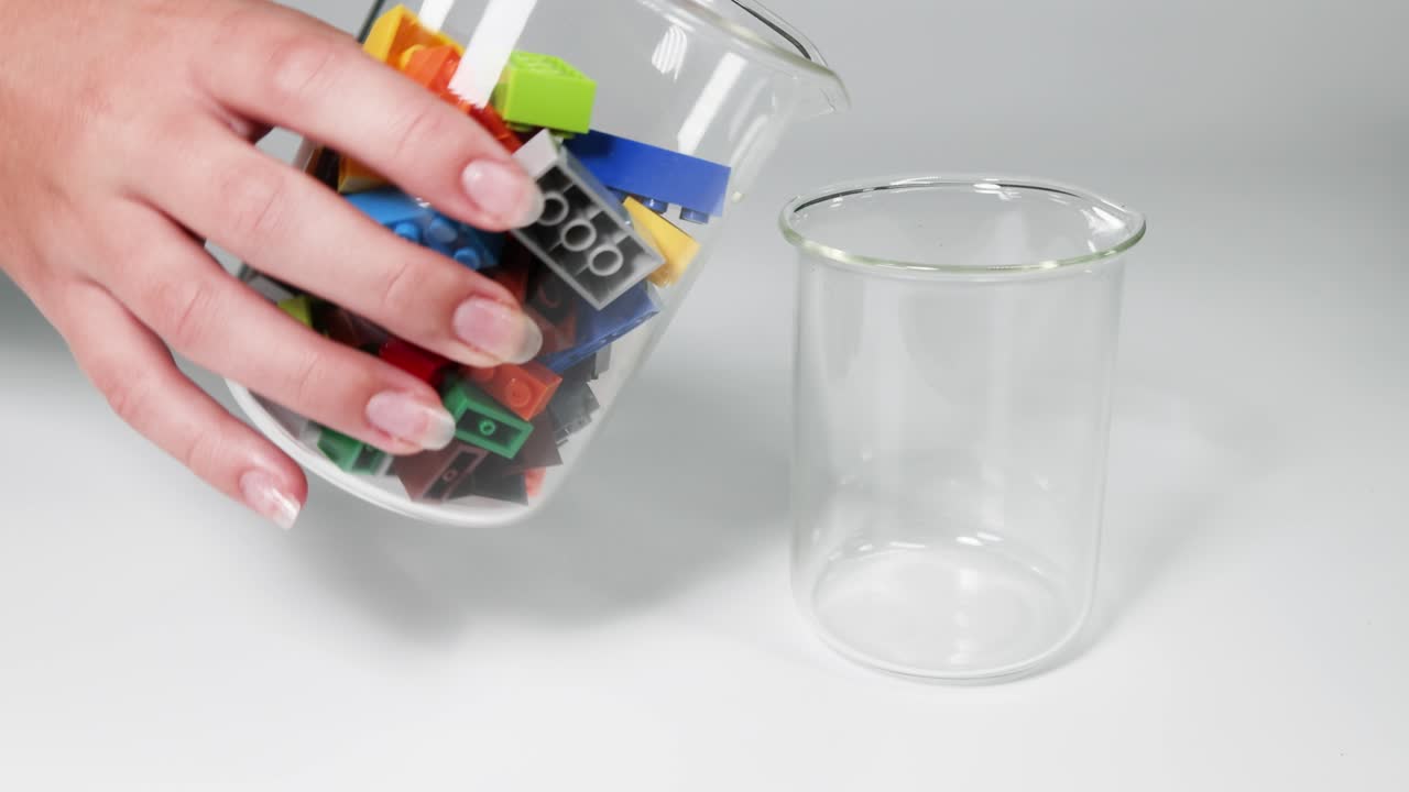 manos moviendo bloques coloridos de un vaso a otro