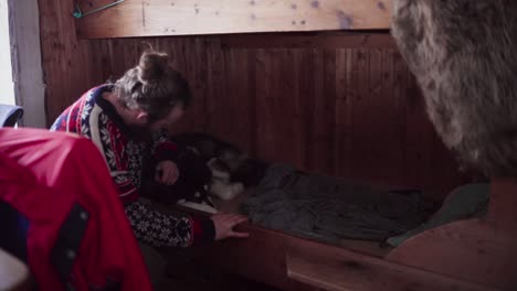 hombre tocando a su perro mascota acostado dentro de la cabaña de madera