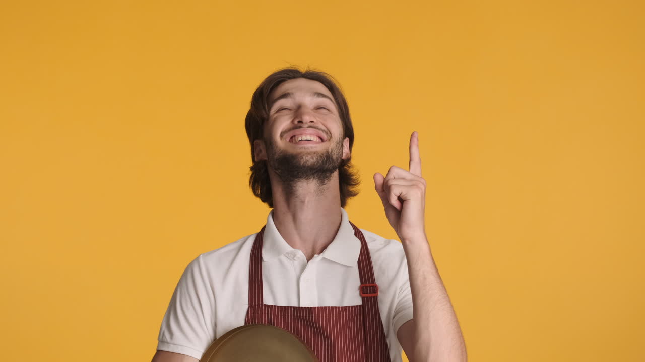 camarero caucásico frente a la cámara sobre un fondo amarillo.