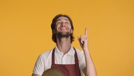 camarero caucásico frente a la cámara sobre un fondo amarillo.