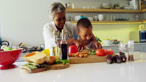 Abuela-Ayudando-A-Nieta-A-Cortar-Verduras-En-La-Cocina-4k