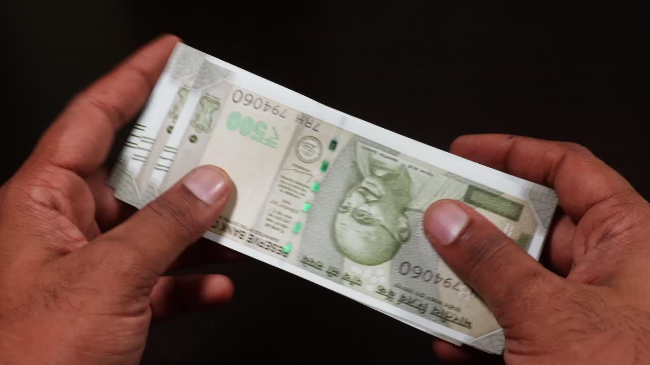 person's hands counting crisp banknotes of Indian 500 rupee currency notes in black background. stable shot, 4k.