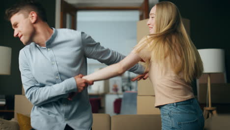 funny couple dancing moving in new apartment full of packed carton boxes closeup