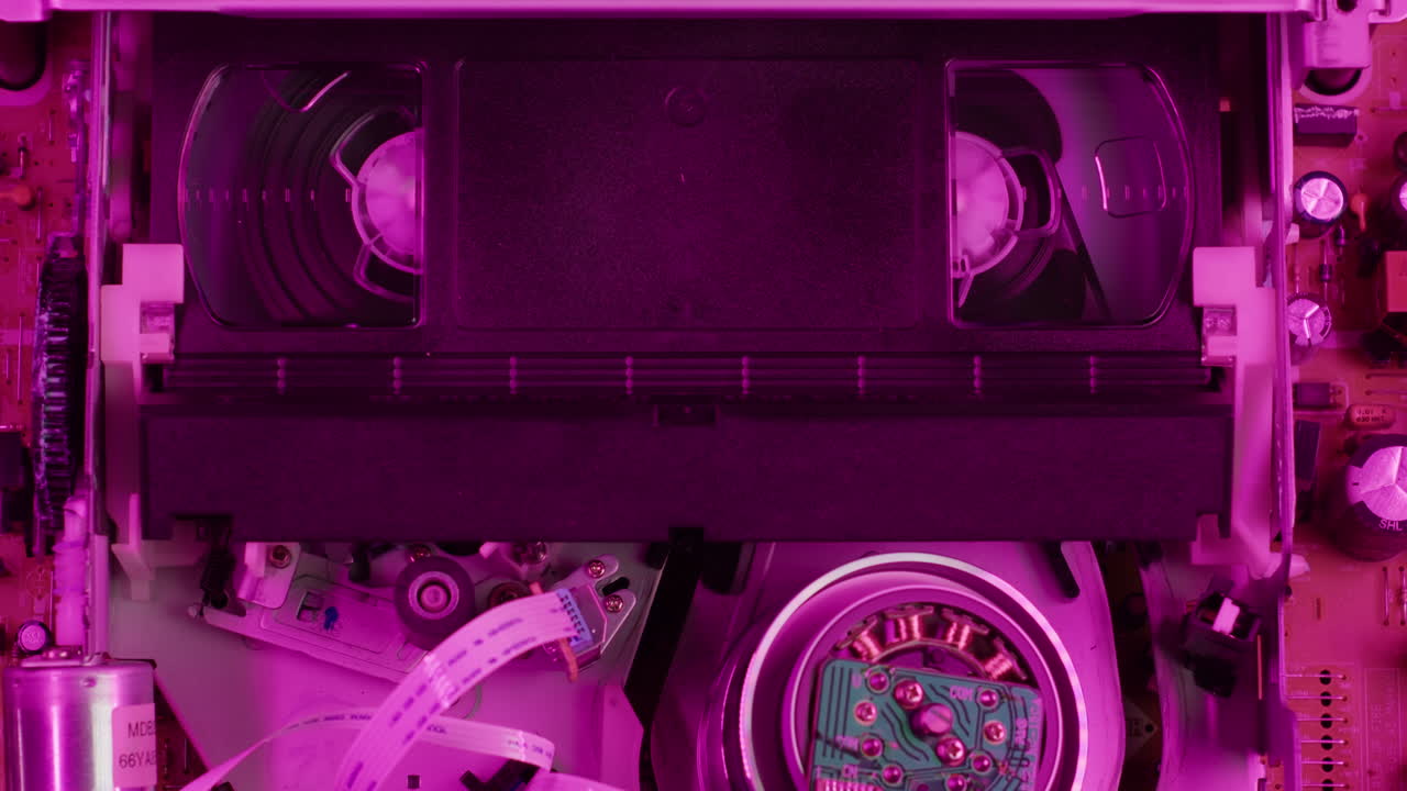 VHS PLAYER, Old video recorder inside in neon pink light close-up, VHS. Retro player in neon blue light, vintage video cassette broadcasting, audio tape.