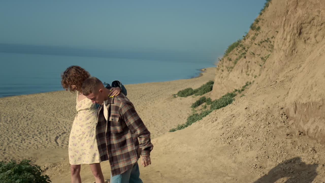 una pareja alegre abrazada caminando por la costa arenosa. una pareja feliz bajando a la playa.