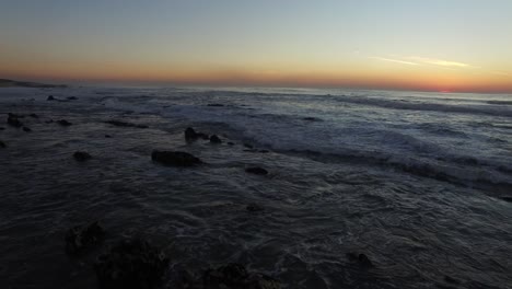 vista aérea de las olas del mar en el cielo naranja de la puesta de sol y el fondo del sol