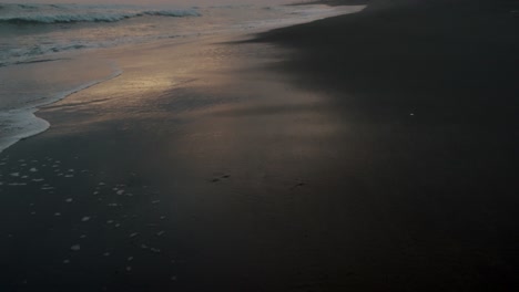 black sand beach of el paredon in guatemala at sunset - drone shot