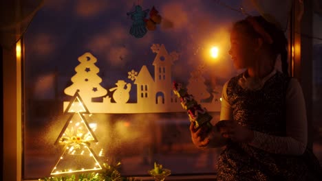 girl looking at christmas decorations by the window at night