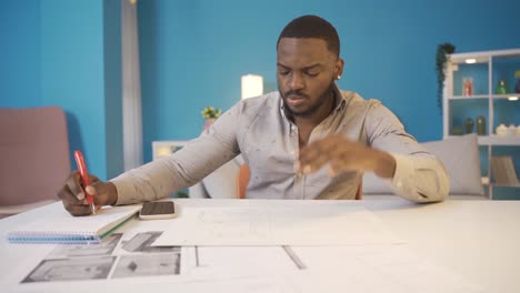 african man working on architectural project. home office work.