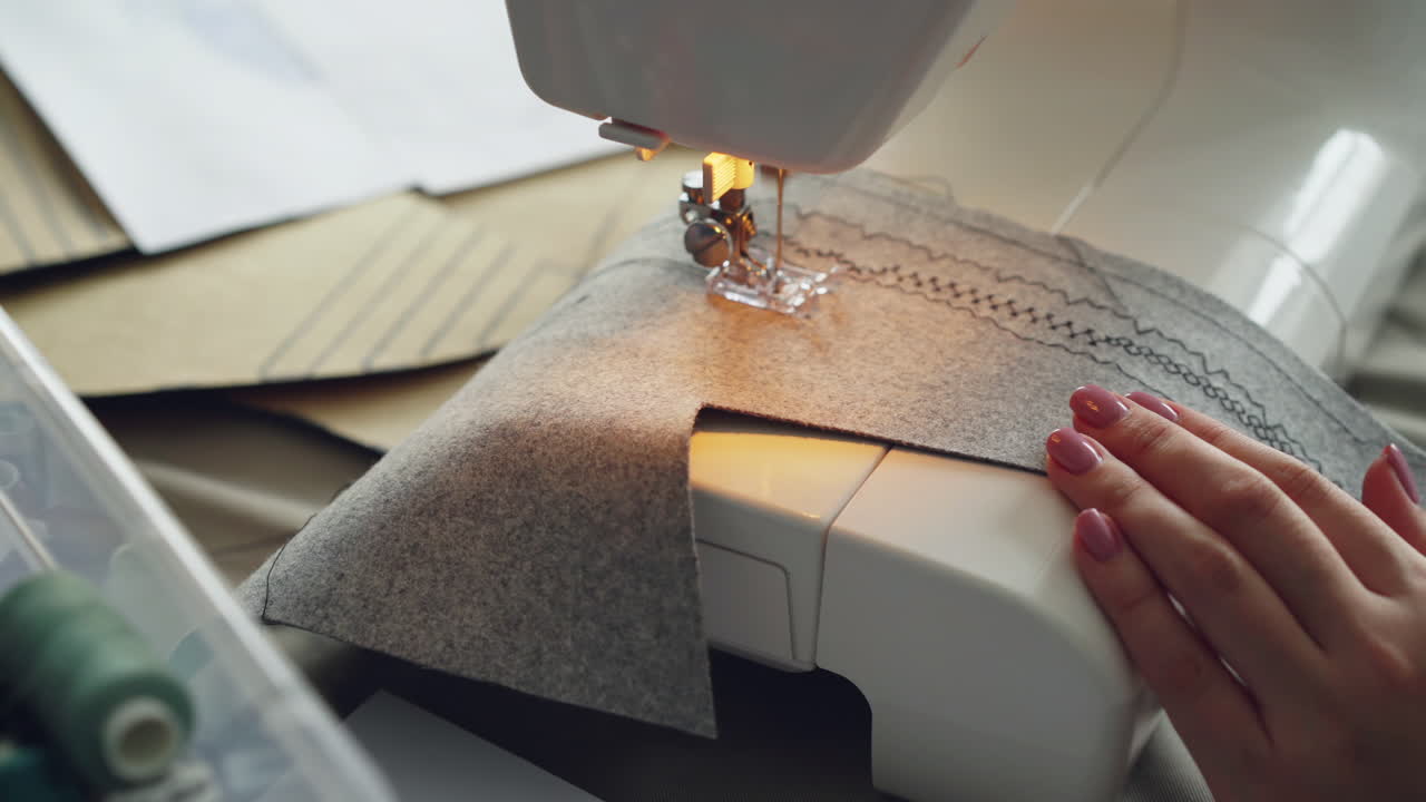 Woman sewing grey fabric on a sewing machine