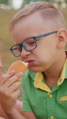 dos hermanos sentados en un campo abierto disfrutando de pasteles recién horneados, sonriendo y compartiendo un momento de alegría mientras disfrutan de la belleza de la naturaleza a su alrededor en un entorno rural pacífico