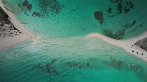 A-turquoise-lagoon-with-sandy-isthmus-and-clear-waters,-aerial-view