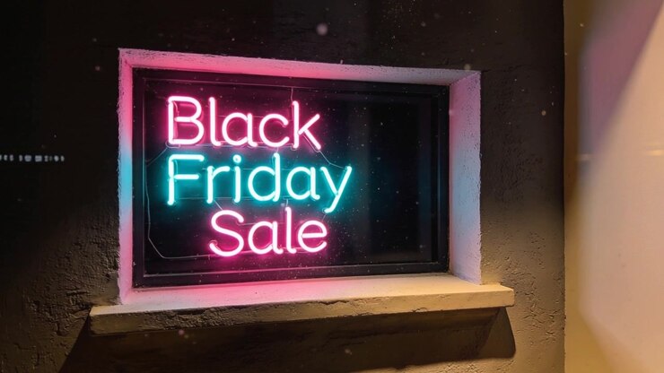 Telecamera che ruota rivelando un'insegna al neon con la scritta Black Friday Sale nella vetrina di un negozio, mostrando una luce calda