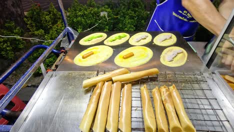 vendor prepares mini pancake rolls in bangkok