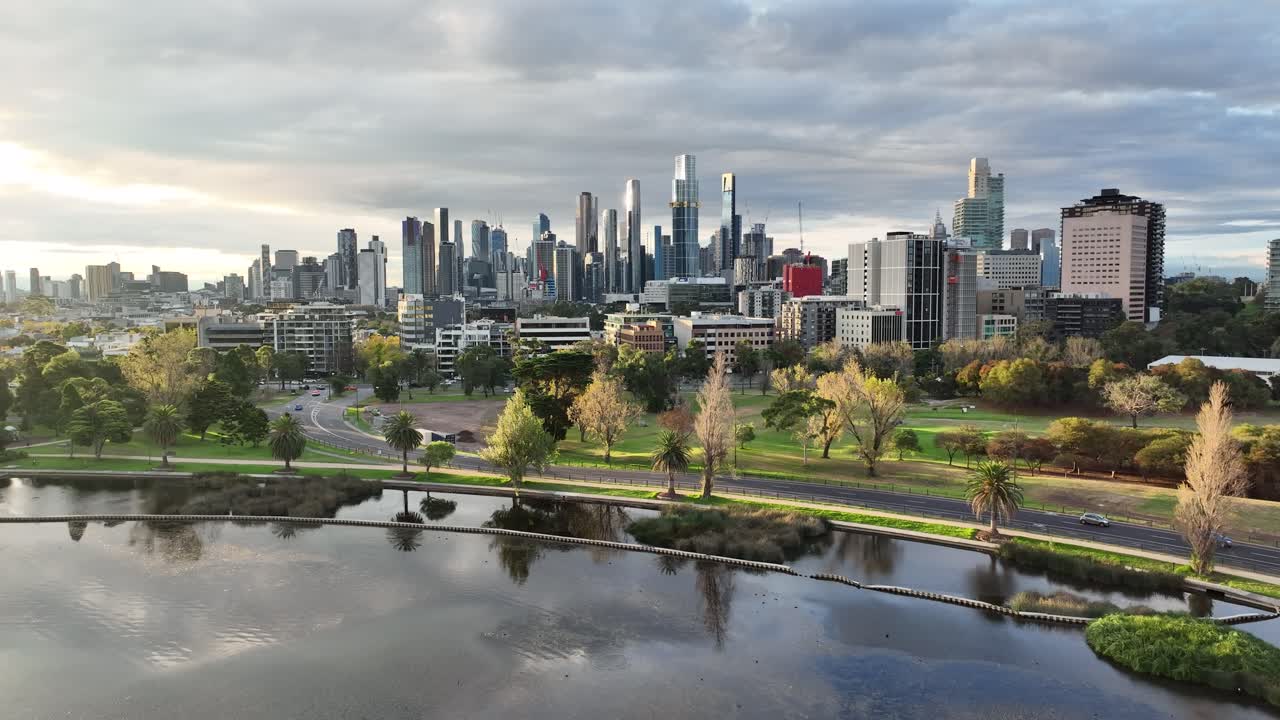 Drone Flight Above Albert Park with Scenic View of Melbourne Skyline on Cloudy Day