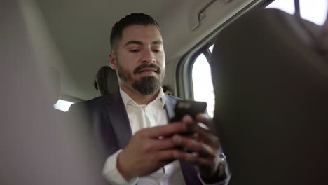 smiling businessman using cell phone in car