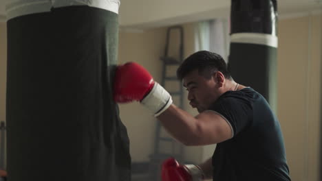 athlete combats punching bag in sports club. aggressive sportsman beats training equipment in empty gym slow motion. martial arts development