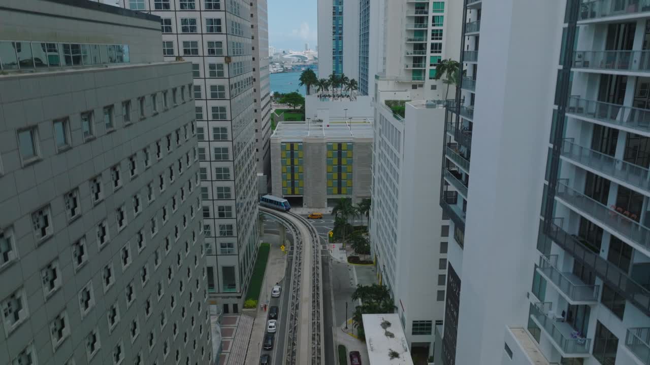 imágenes aéreas ascendentes de vagones de tren conduciendo en vías que conducen entre edificios de gran altura. concepto futurista de transporte de pasajeros. miami, ee.