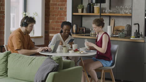 three  roommates sitting together at kitchen table at home