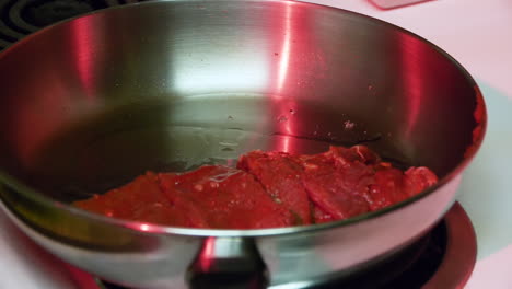 freír carne en una sartén bajo una espeluznante luz roja