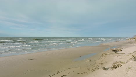 Aerial-establishing-view-of-Baltic-sea-coast,-sunny-day,-white-sand-seashore-dunes-damaged-by-waves,-pine-tree-forest,-coastal-erosion,-climate-changes,-wide-angle-drone-shot-moving-backward-low