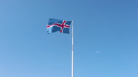 toma aérea de la bandera de islandia ondeando en el fondo del cielo azul