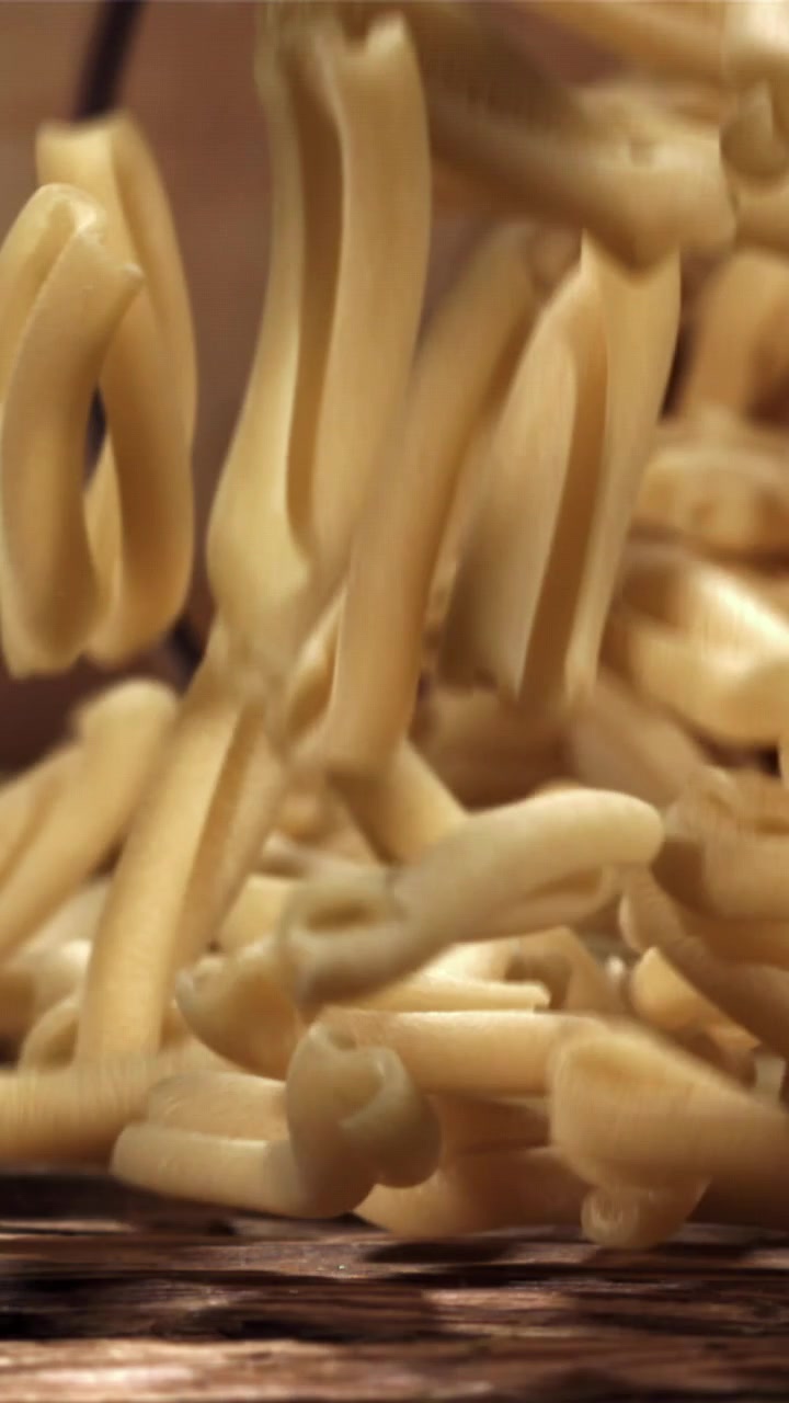 Pasta italiana secca che cade al rallentatore su un tavolo di legno