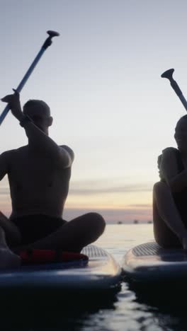 couple paddleboarding at sunset