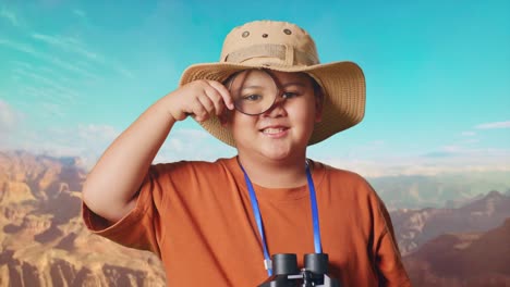 asian boy with a hat and binoculars looking through the magnifying glass examines something while traveling at the top of mountain. boy researcher, travel tourism adventure concept
