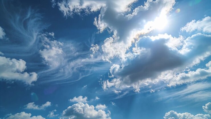 Le soleil apparaissant derrière un nuage cumulus, le ciel montrant des rayons de soleil, des traînées de cirrus se déplaçant