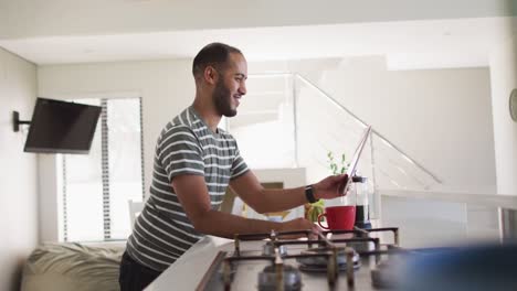 Smiling-mixed-race-man-using-tablet-in-kitchen