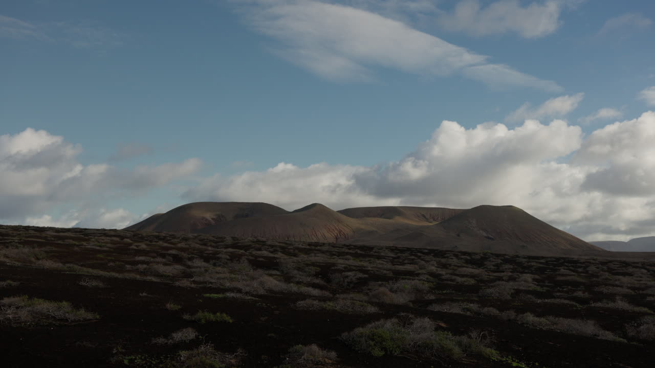 vista a la montaña en la graciosa, lanzarote, con mínimas nubes y vegetación seca.