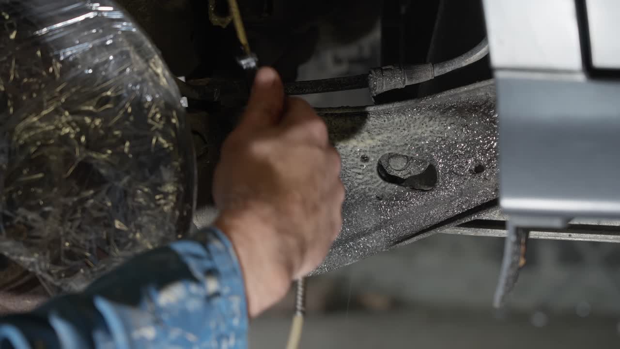 Lanolin rust protection being applied to flat structural piece with precision spray nozzle behind rear brake disc to guard against corrosion