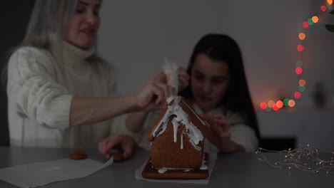 familia decorando la casa de pan de jengibre en la víspera de navidad