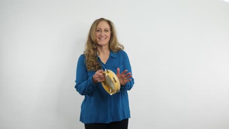 a red-haired  music teacher is playing the tambourine while smiling