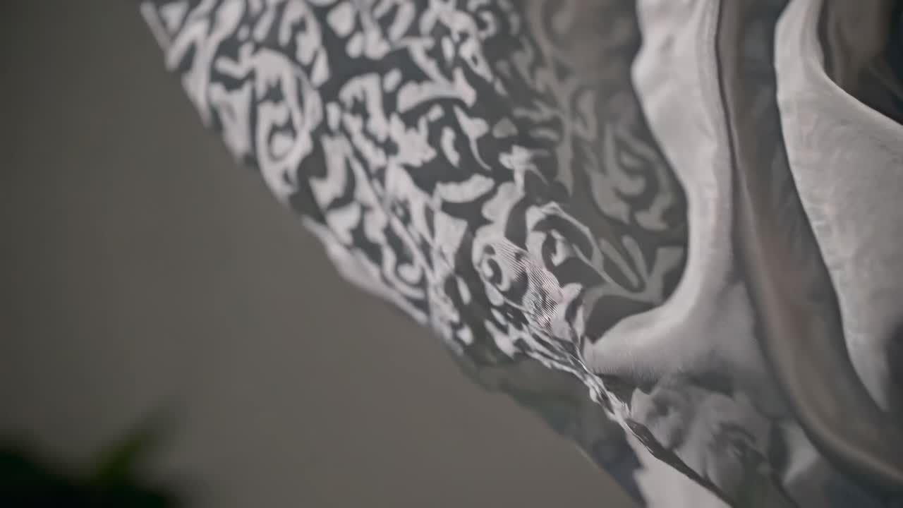 Close-up video of flowing fabric with intricate patterns, captured from a low angle