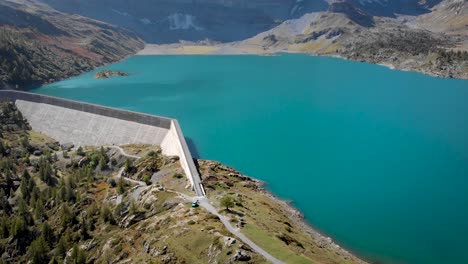 Aerial view of Lac de Salanfe and its hydroelectric dam in Valais, Switzerland on a sunny autumn day in the Swiss Alps with a pan up view from the turquoise waters up to alpine peaks and cliffs