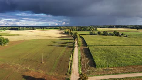 Empty-gravel-road-surrounded-by-endless-farm-fields