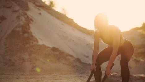 primer plano de una niña con una cuerda realiza entrenamiento al aire libre en el suelo arenoso cerca de la playa. cuerda en las manos de las mujeres al atardecer