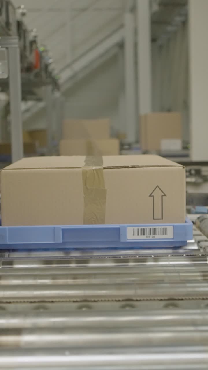 Cardboard box on conveyor in a busy warehouse, focus on logistics process