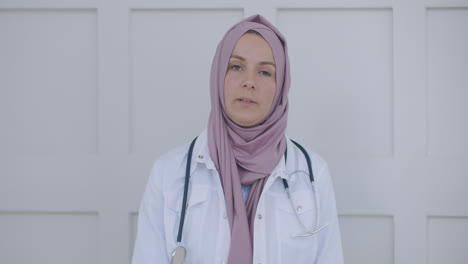 arab muslim woman in hijab doctor via video conference. portrait of a female muslim doctor. female healthcare professional wearing scrubs and a hijab sitting on the stairs at a hospital