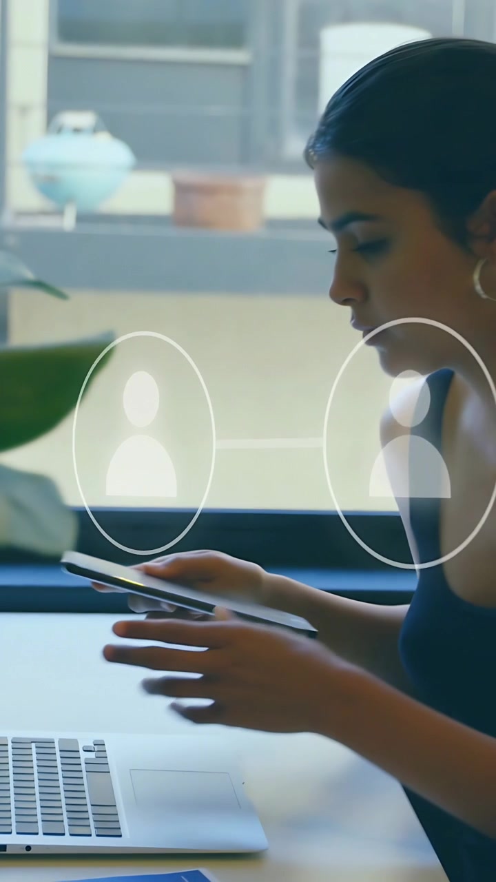 Vertikal video: Kvinde lægger telefon på skrivebord, tager tablet og skriver, mens hun bruger et tech-overlay.