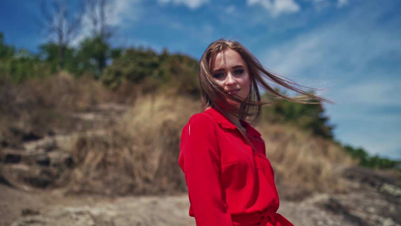 Portrait of a smiling girl outdoors. Beautiful young woman looking at camera. Happy attractive female with long hair standing in nature.