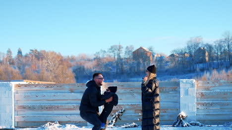 happy mom and dad play with their baby outdoors in winter. father tosses his son up entertaining him.