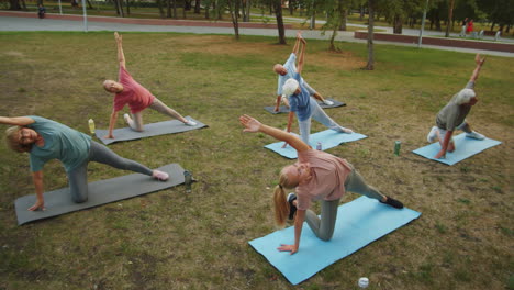 maestro de yoga y personas mayores practicando la postura de la puerta en el parque