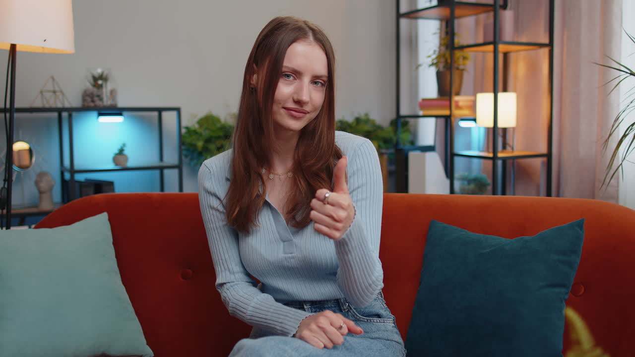 여자아이가 엄지손가락을 올리고 승인을 위해 고개를 끄덕이는 것은 성공적인 좋은 일, 집에서 만족스러운 결과입니다.