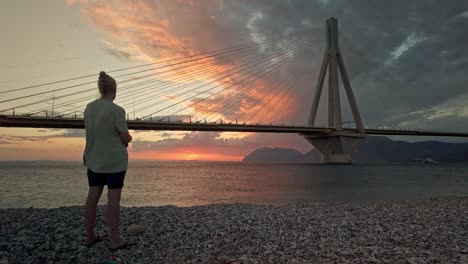 person watching sunset over the ocean with a bridge in the background