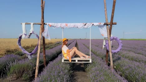 wide shot of hippie-style young woman relaxing on a pallet swing