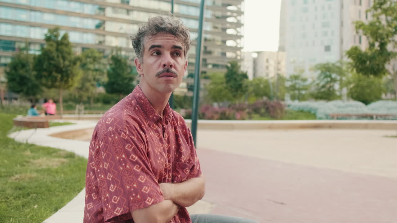 Thoughtful Man with Mustache Sitting in an Urban Park
